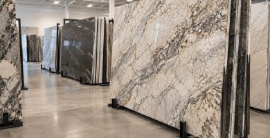 Large natural stone slabs displayed vertically in a countertop showroom, including granite and quartzite with varied veining patterns.