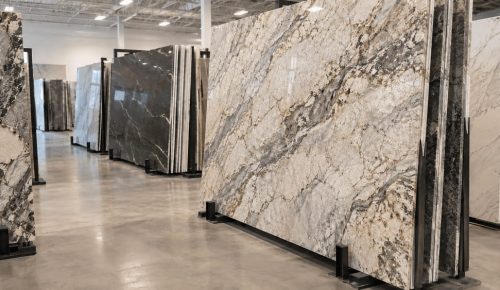 Large natural stone slabs displayed vertically in a countertop showroom, including granite and quartzite with varied veining patterns.
