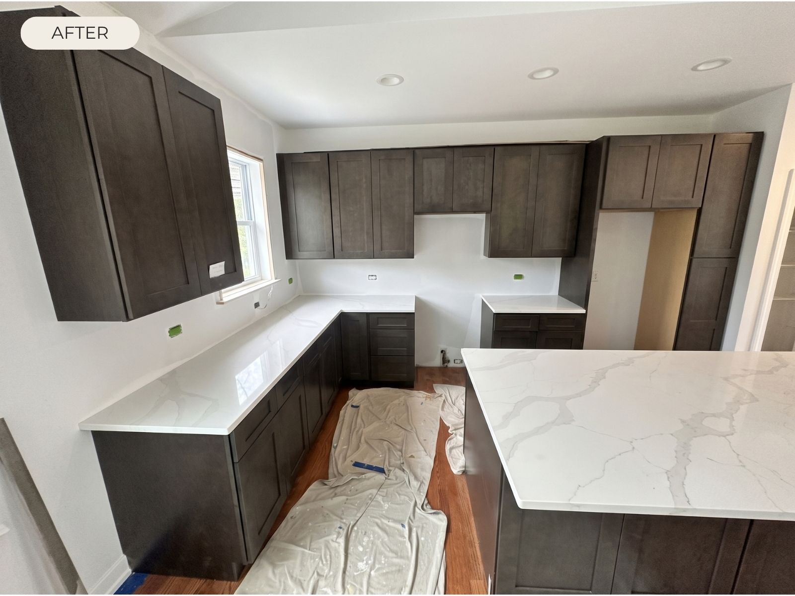 dark-kitchen-white-countertop-after-installation White countertops with gray veining installed in a kitchen with dark cabinets and a large island